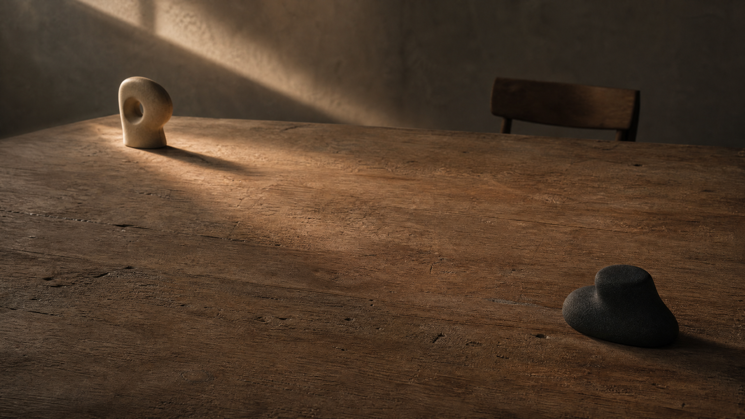 A quiet warm-toned table with two abstract unbranded objects placed apart in soft afternoon light.